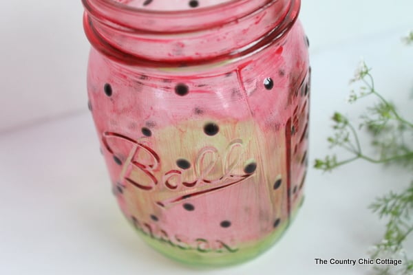 Watermelon Mason Jar -- learn how to paint a great watermelon mason jar craft for summer. Perfect for decorating your home or for parties. The jar turns out see through so you can add candles easily.