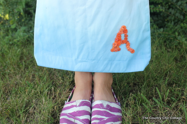 A great button monogram tote for back to school. Perfect for the student, teacher, or a special gift for mom to carry herself. Make your own ombre tote in a few simple steps. Close up of an ombre dyed monogrammed tote bag with the letter A in the bottom corner.