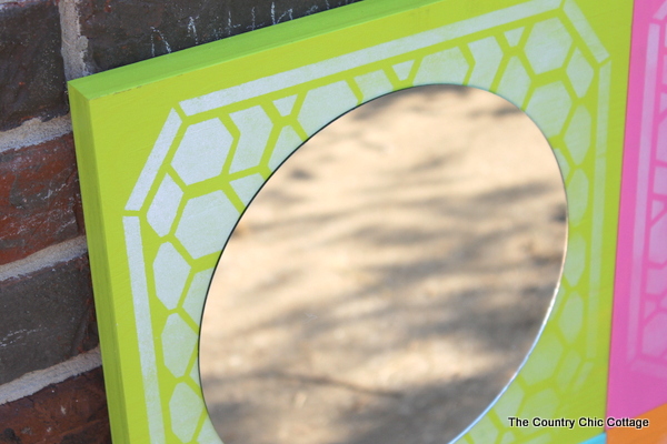 DIY Color Block Mirror -- make this mirrored art for any room in your home easily with a few simple steps. Click to see where to buy the boards, mirrors, paint and stencils to make this great mirror! closeup of circle mirror on painted wood square