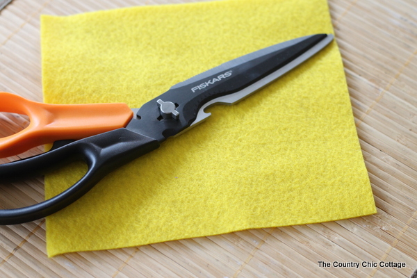 A quick and easy way to add a unique handmade touch to your packages and gifts. Click to see how to make this great DIY gift wrap. square felt and scissors to make DIY gift wrap topper
