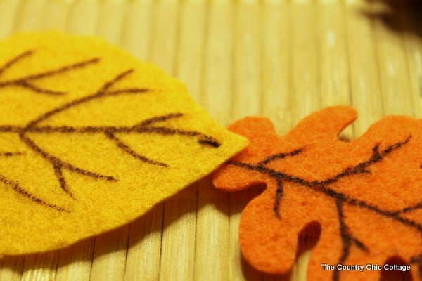 Fall Felt Leaf Garland -- add this to your fall decor. Super simple to make with pre-cut felt leaves and some thread. Come get the full instructions. closeup showing small front stitch holding two leaves together
