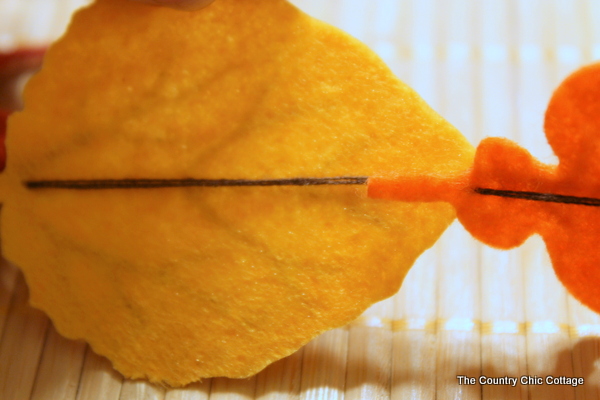 Fall Felt Leaf Garland -- add this to your fall decor. Super simple to make with pre-cut felt leaves and some thread. Come get the full instructions. closeup showing sewing process