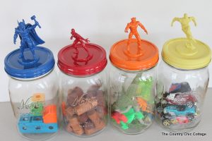 four jars with superhero toys on top