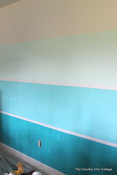 How to Paint a Gradient Wall -- learn how to get that ombre or gradient look on the wall of your home with this method. This wall looks like a paint chip with horizontal lines running through it. The post even shows how to do the math and calculate where your lines go! Here's a look at our gradient wall after the first coat of paint