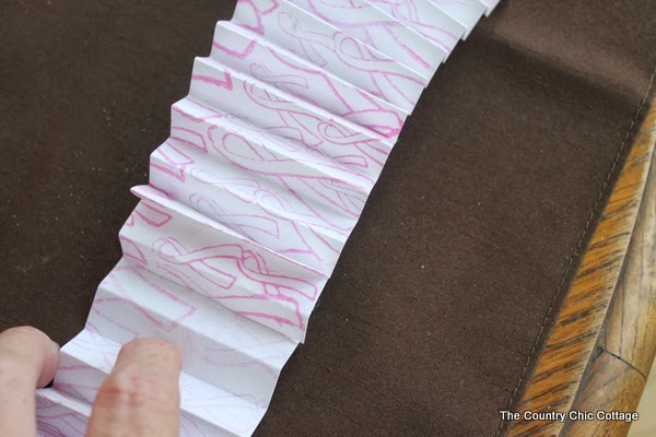 folding breast cancer paper into an accordian