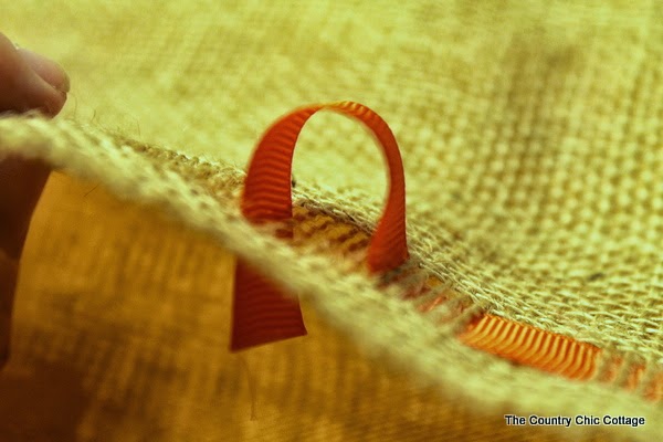 DIY Burlap Thankful Place Mats -- the perfect place mats to make for your Thanksgiving feast. Super simple to make and you can use the word "thankful" or the word of your choice. ribbong going through burlap