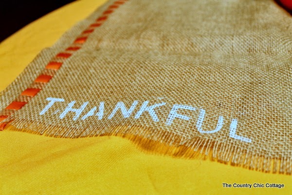 DIY Burlap Thankful Place Mats -- the perfect place mats to make for your Thanksgiving feast. Super simple to make and you can use the word "thankful" or the word of your choice. thankful written in paint on burlap placemat