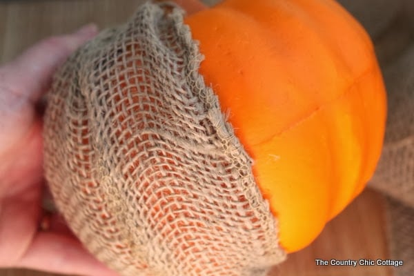 Use hot glue to secure the burlap ribbon to your pumpkin