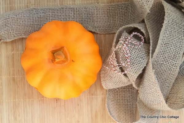 Supplies you need to make a burlap pumpkin: a dollar store pumpkin and burlap ribbon