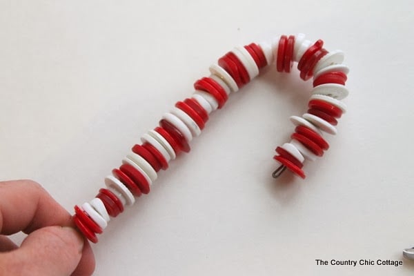 Button Candy Cane Christmas Ornaments -- handmade ornament tutorial that will have your tree full of button candy canes in no time. assembling white and red candy cane ornament