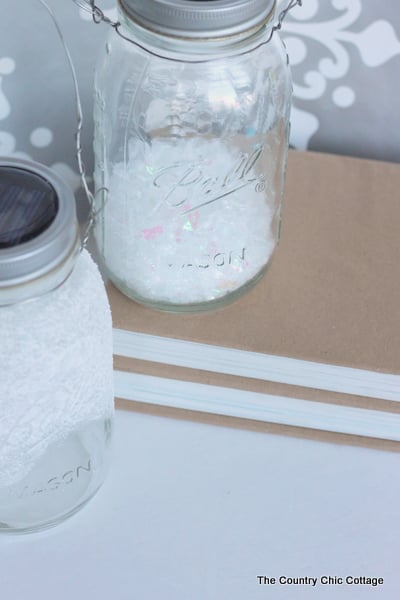 Solar Mason Jar Lights -- add tops to your mason jars and use solar power to light up the outdoors. Solar Mason Jar Lights with glitter snow