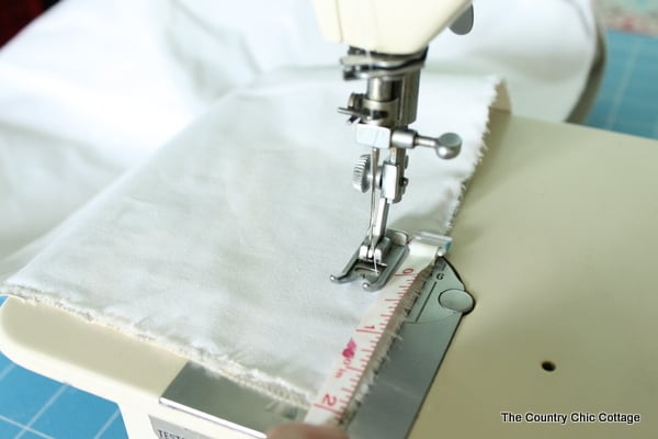 fabric on sewing machine with tape measure to determine where to sew the hem