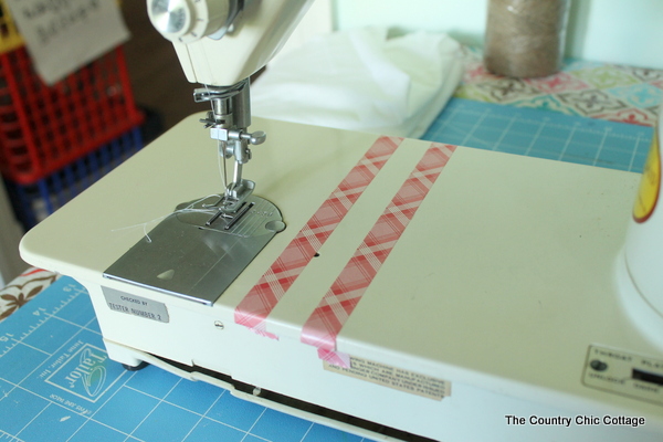 sewing machine with strips of tape to help indicate where to sew seams for curtains