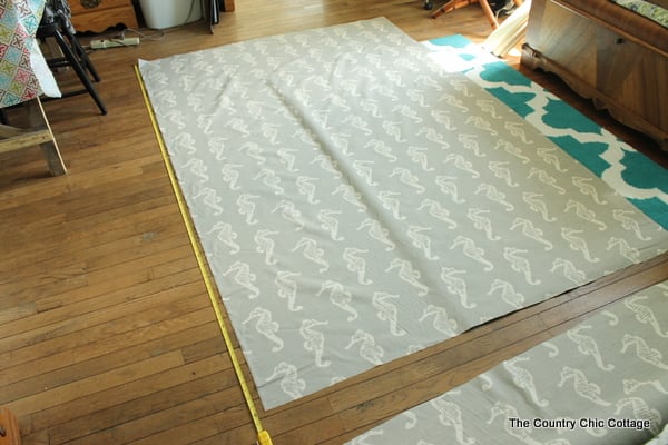 fabric laid out on floor with measuring tape measuring the length