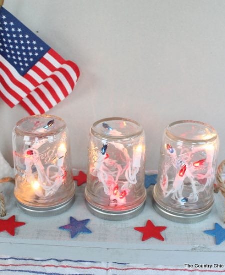 Patriotic Mason Jar Centerpiece for the Fourth of July -- make this centerpiece and light up your party in style! A fun way to add string lights to your table in mason jars! Easy to make by following this craft tutorial.