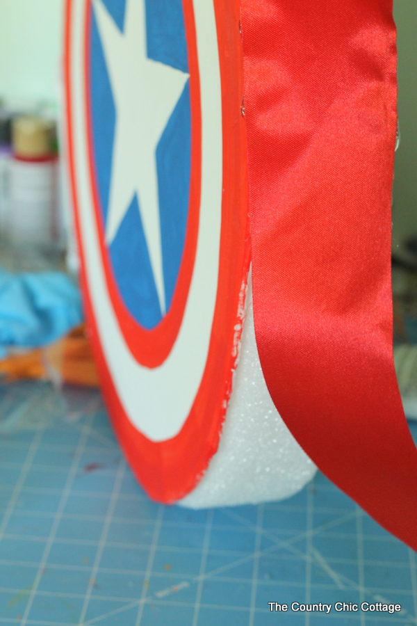 Wrap a ribbon around the edge of the Captain America Shield, covering the foam wreath