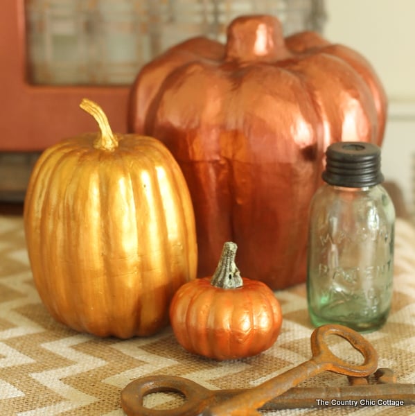 Metallic Painted Pumpkins on a table with a glass bottle 