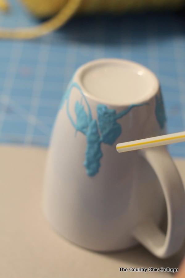 Blowing air through a straw to create a marbled look on a mug