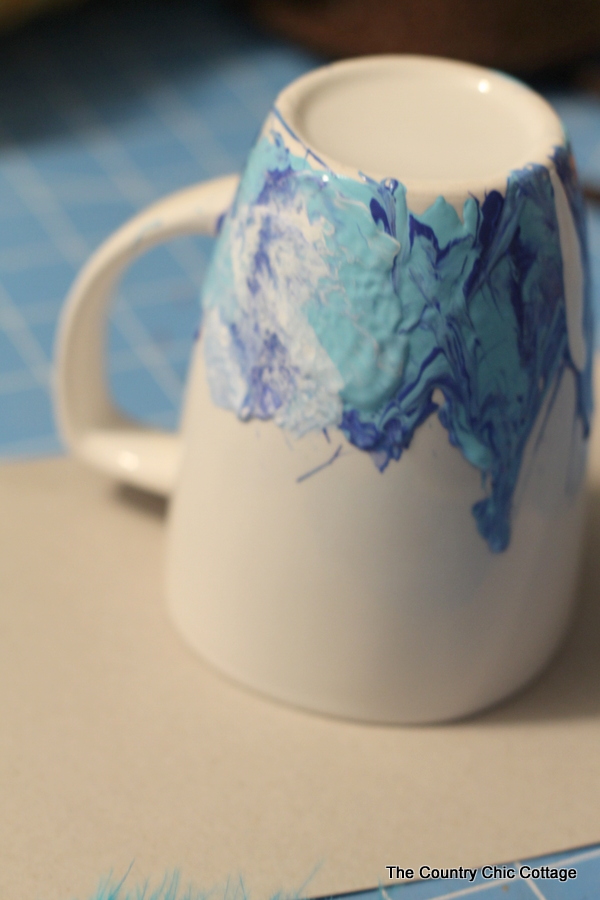 Mixing the white paint into the other blue paints on the white coffee mug