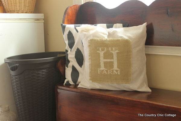 A bench with burlap pillow that reads "The H Farm"