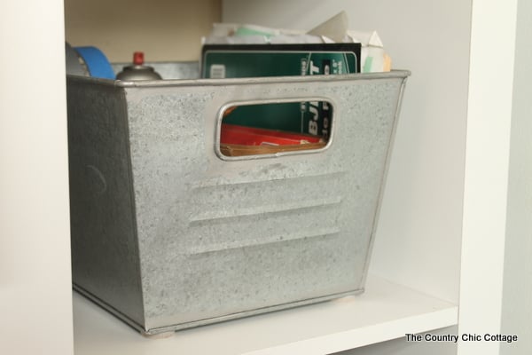 Galvanized metal bins holding tools and books in mudroom.