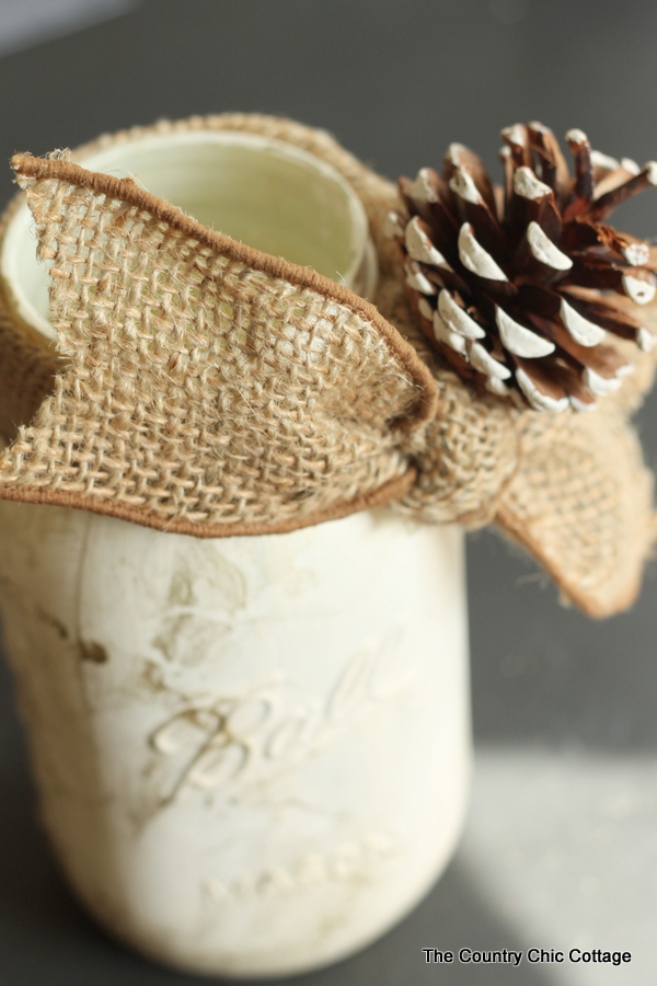 burlap ribbon and pine cone on gold marbled mason jar