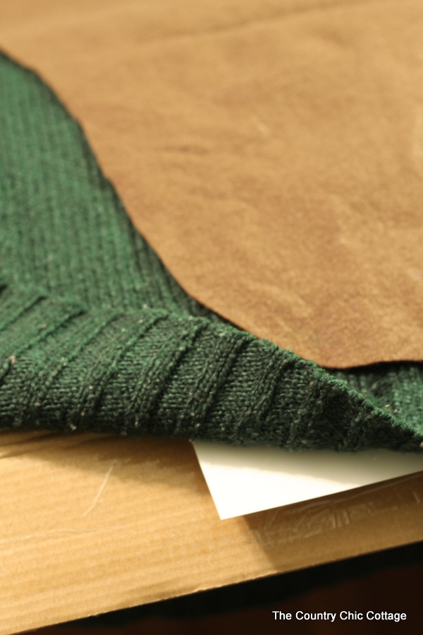 close up of a diy ugly sweater with the bottom folded back to show a piece of cardboard in between the front and back.