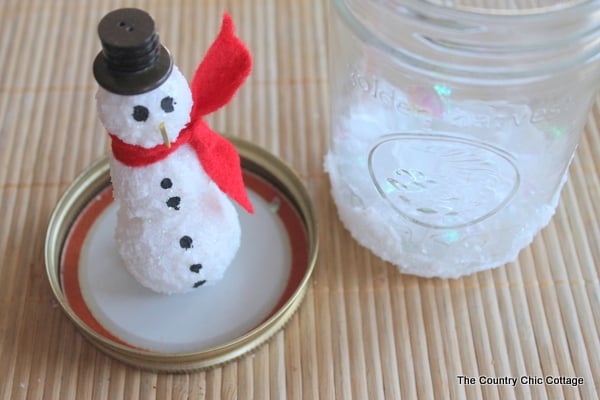 gluing the snowman to the lid for mason jar snow globes