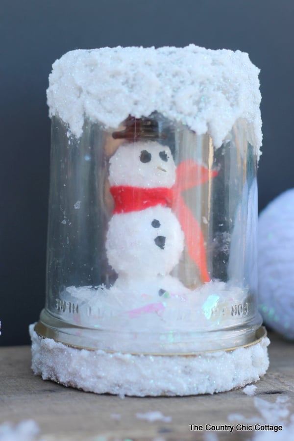 closeup of a mason jar snow globe with a snowman inside