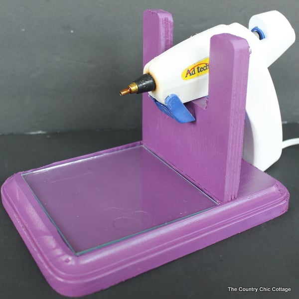 Finished DIY purple hot glue gun holder, white hot glue gun resting in stand, on dark gray background