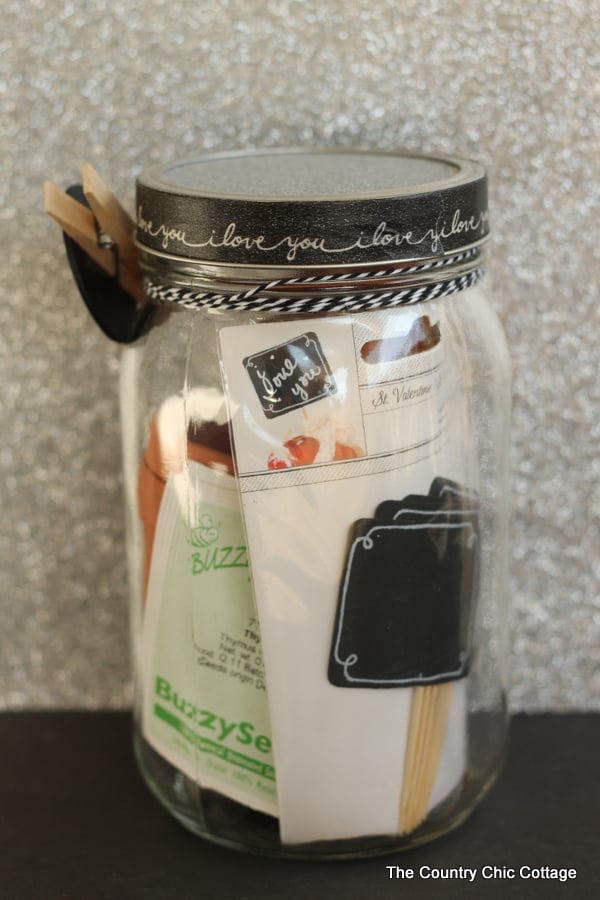 Quart sized mason jar filled with seed packets, mini clay pots, garden markers and more.