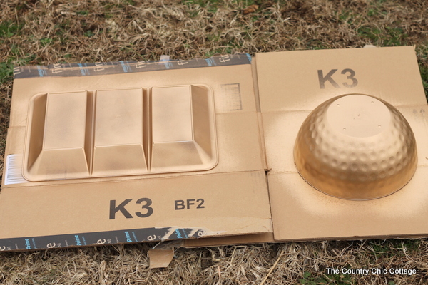 bowls and divided organizer upside down on cardboard and spray painted gold