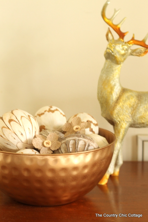 gold bowl with home decor items and deer decor in background