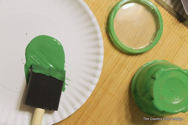 Green paint on a white paper plate with a sponge brush