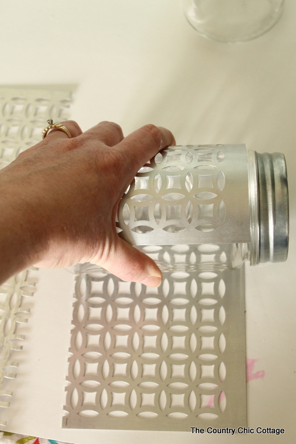 rolling metal piece around mason jar to shape it