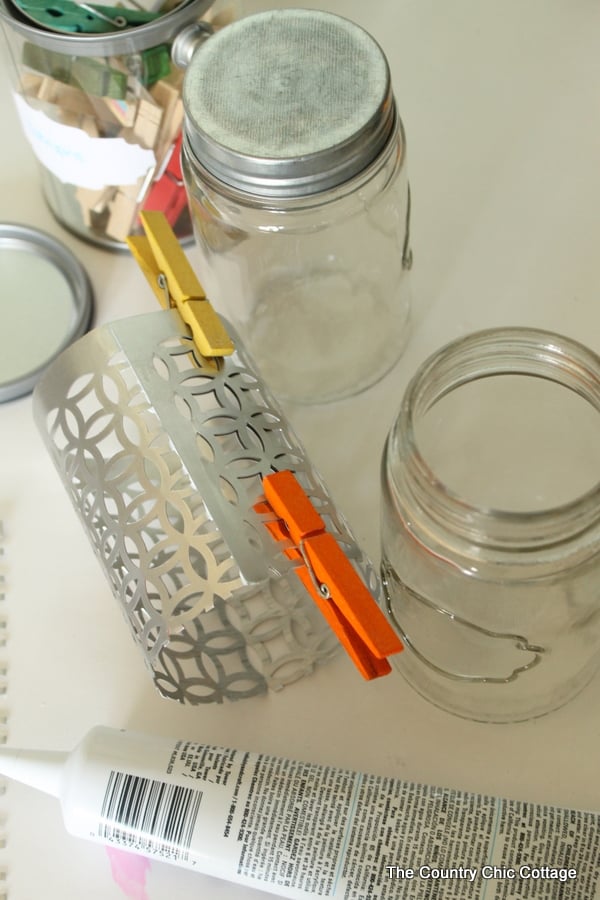 clothespins clamping metal together while glue dries for jar candle holder