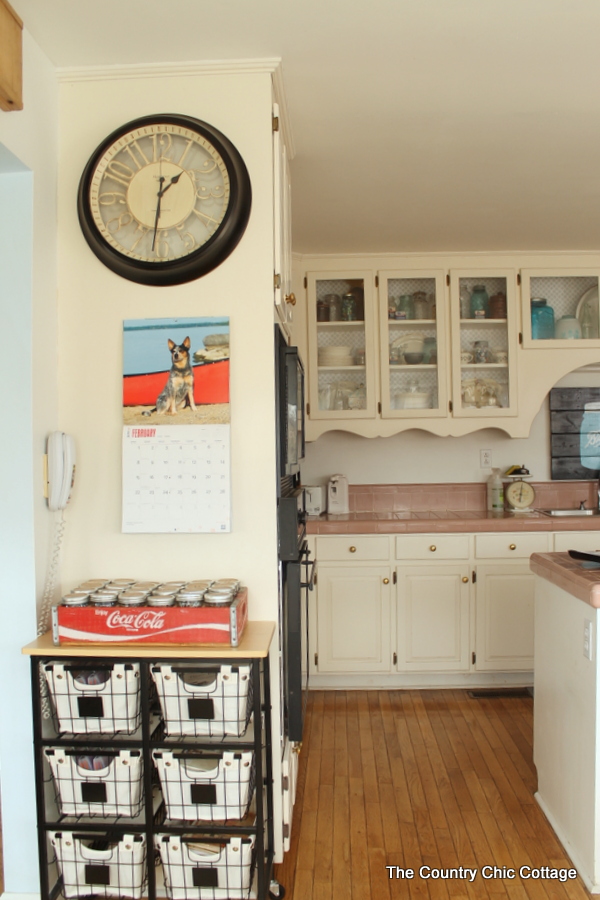 Rustic kitchen decor including iron roll away cart with baskets and a mason jar organizer on top.