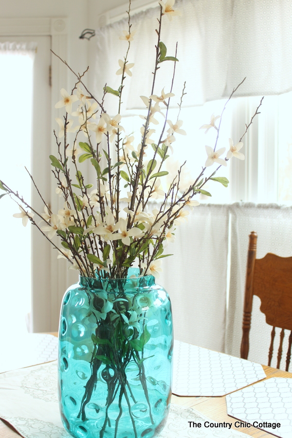 blue glass vase with flowers on kitchen table