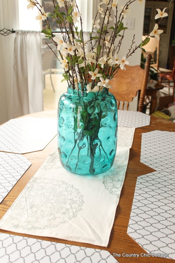 DIY placemats and table runner with blue glass vase of flowers on the table