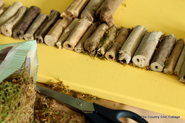 adding cut driftwood pieces back onto the canvas