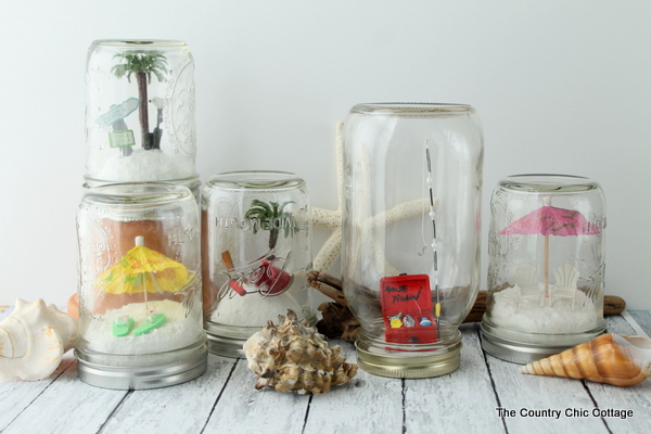 Collection of five beach mason jars with miniatures in them.
