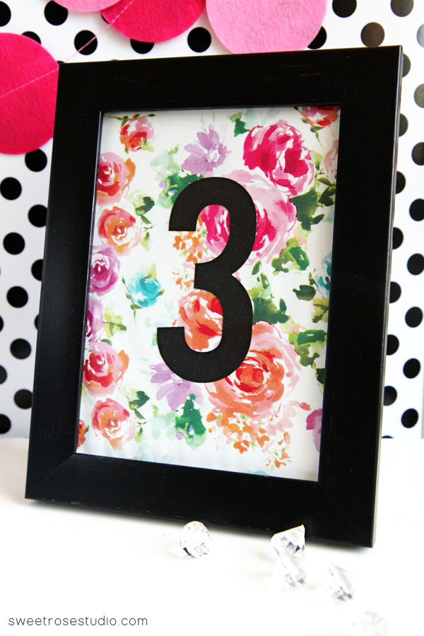 number in black with roses in background in a black frame