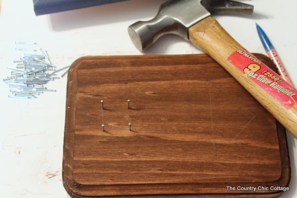 Hammer nails into wood plaque