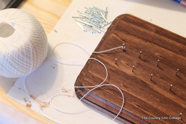 Knot string around the first nail to begin geometric string art pattern
