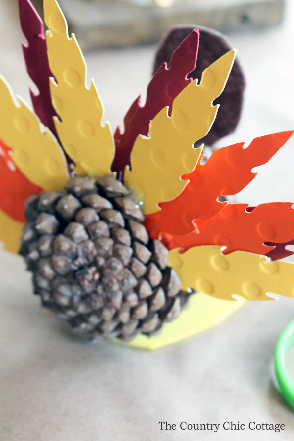 gluing the feathers into a pinecone