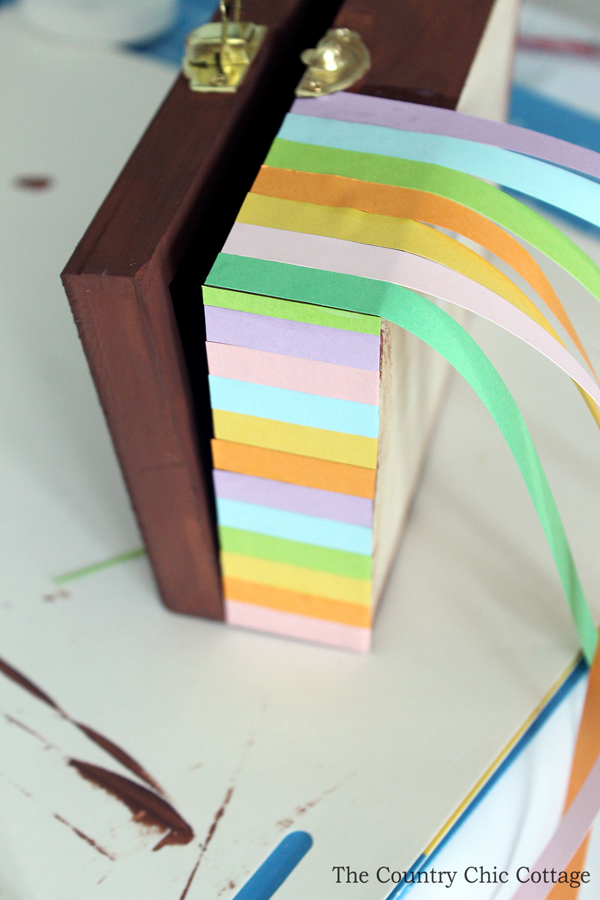 colored strips of paper hanging over edge of wooden box