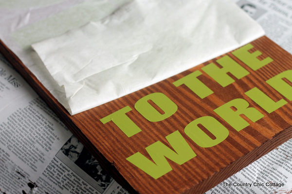 removing transfer paper to see vinyl lettering on wood board