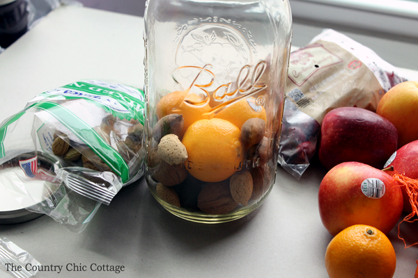 adding nuts to the bottom of a mason jar with oranges