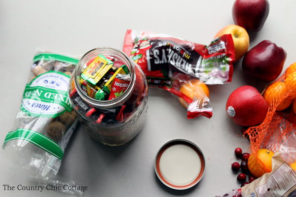 adding chocolates to the top of an assembled fruit basket jar