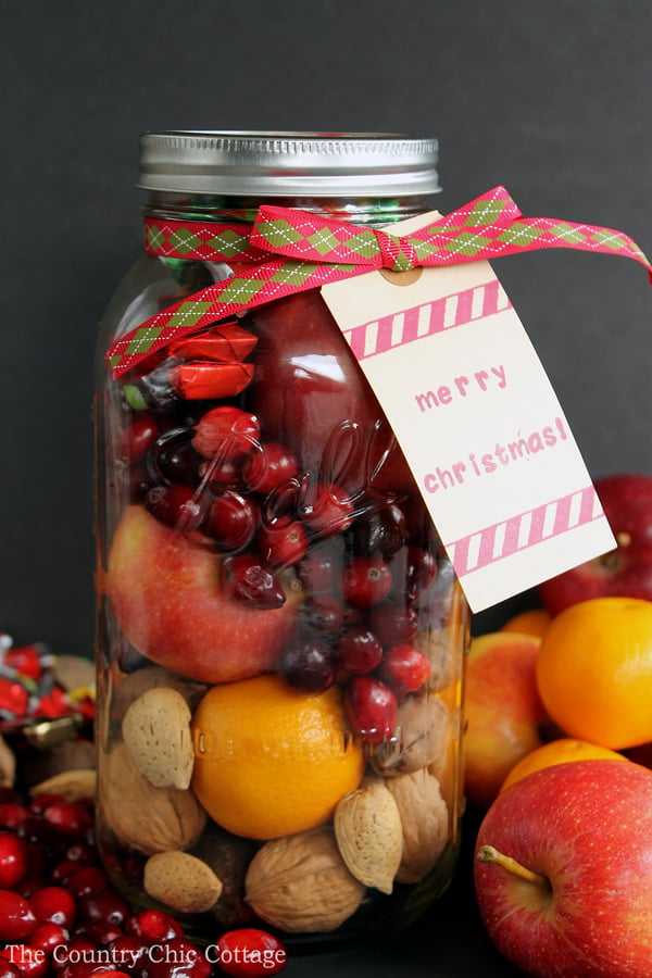 assembled fruit basket in a mason jar surrounded by fruits with gift tag